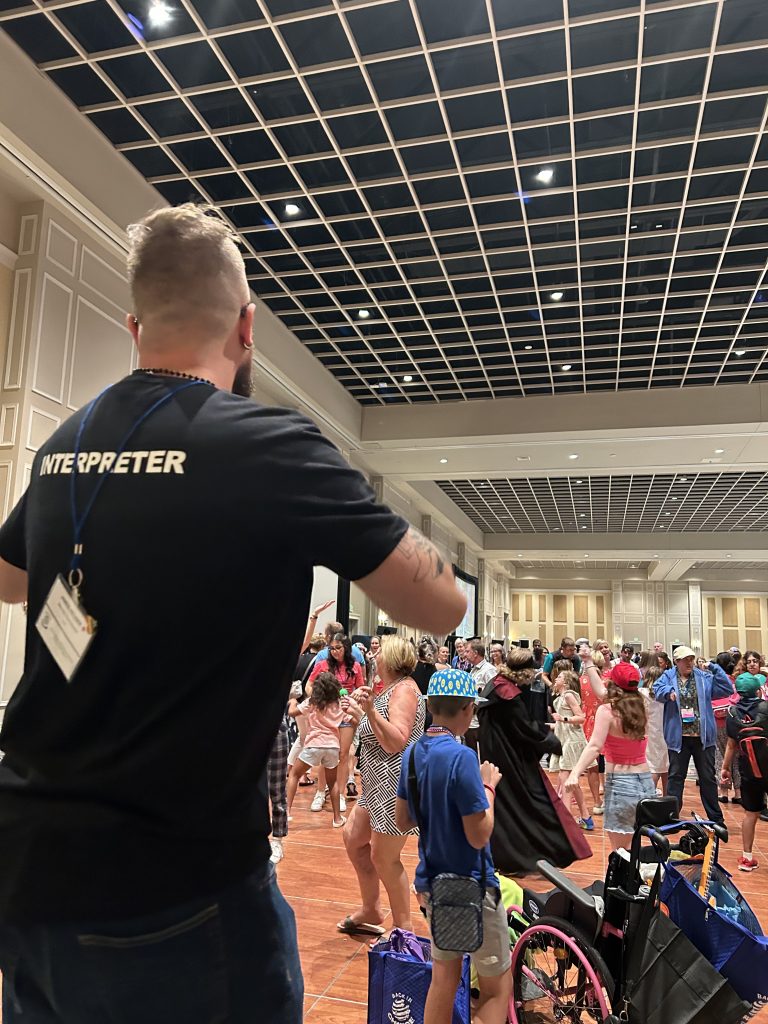 Interpreter supporting communication at a diverse, accessible indoor gathering.
