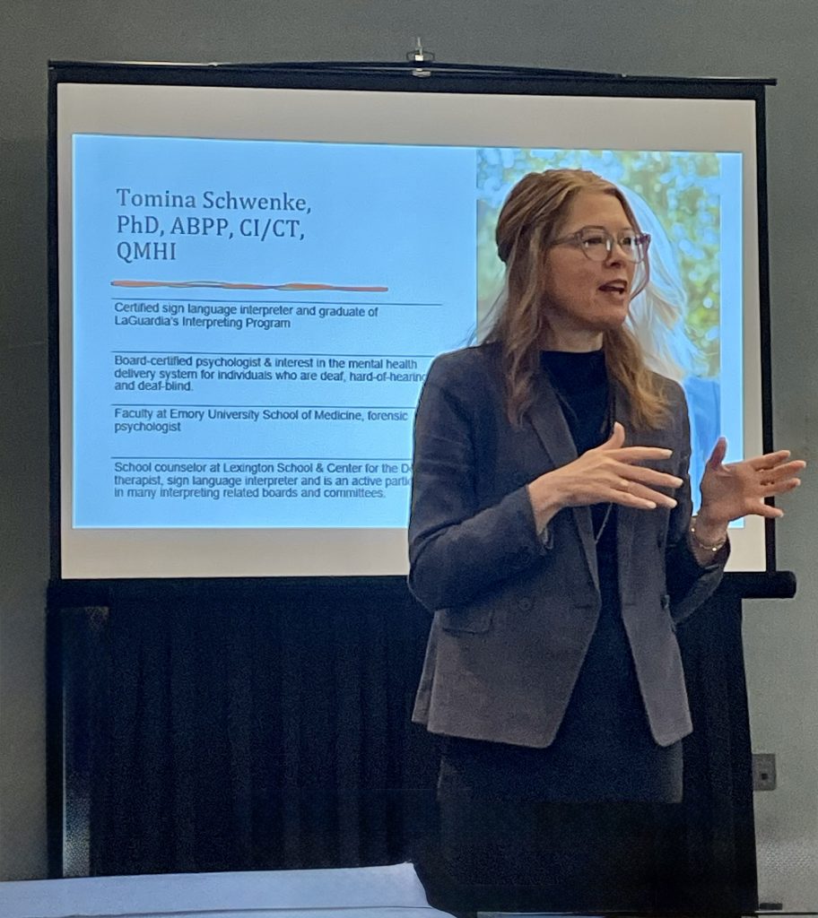 Presenter discussing inclusive mental health services with slide showing professional background.