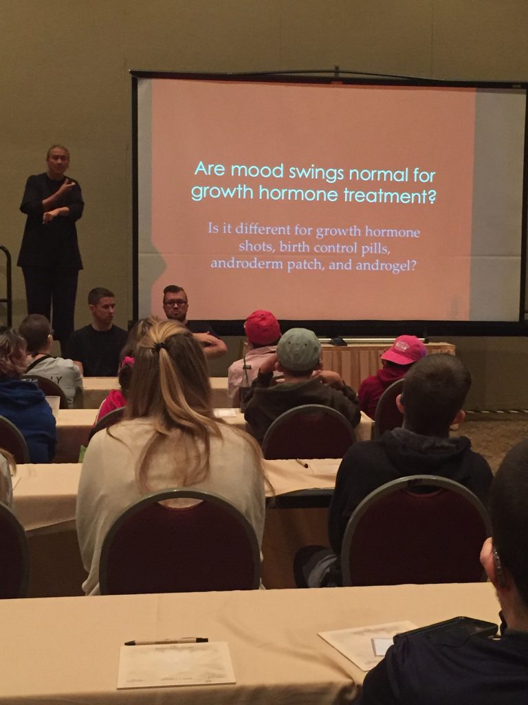 Presenter speaking at a seminar with slide discussing hormone treatment and mood changes.