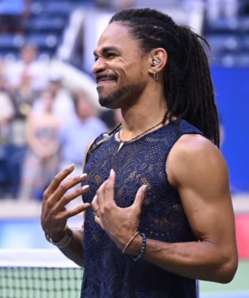 An interpreter signing at a tennis stadium, hands raised to the chest.